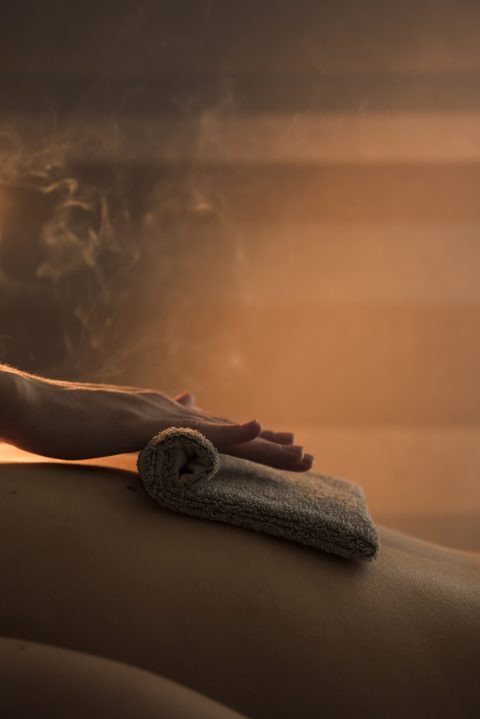 close-up-therapist-hand-massaging-woman-s-back-with-hot-towel-spa